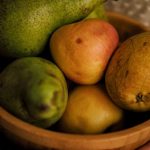 A wooden bowl holding an assortment of pears and apples, highlighting healthy eating.